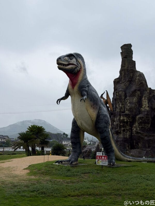 曇り空の下に立つティラノサウルスのオブジェ | iphone review.jp iPhone 17 Pro カメラ 曇り空の下に立つティラノサウルスのオブジェ